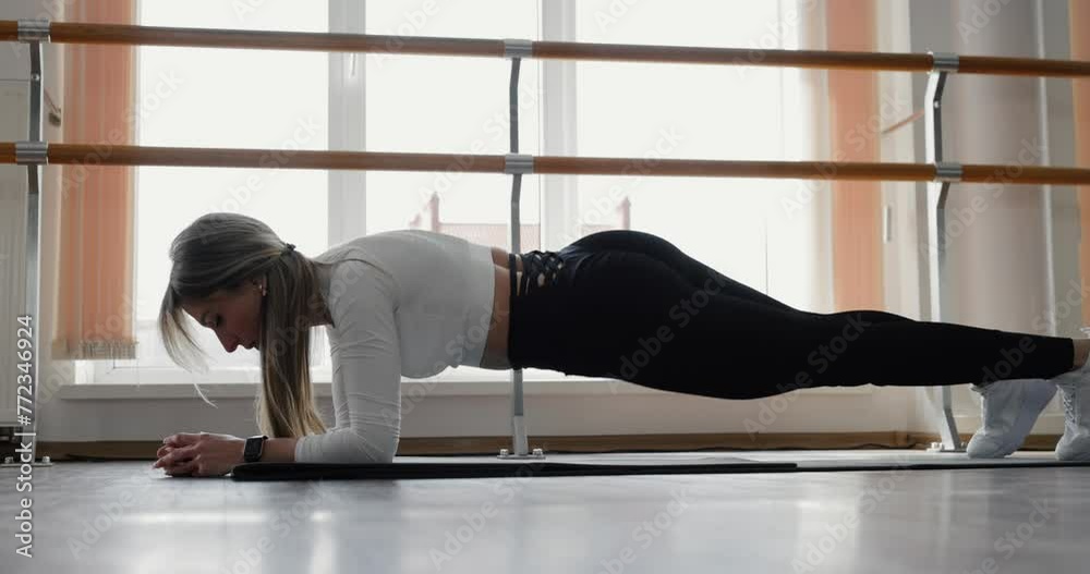 Training abs and core muscles, woman doing plank on a mat at the gym