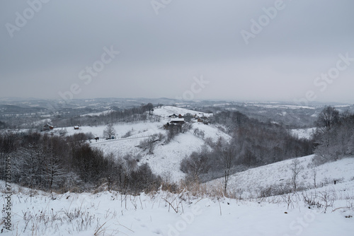 Farm on hill in winter, hilly village landscape during cold day with snow
