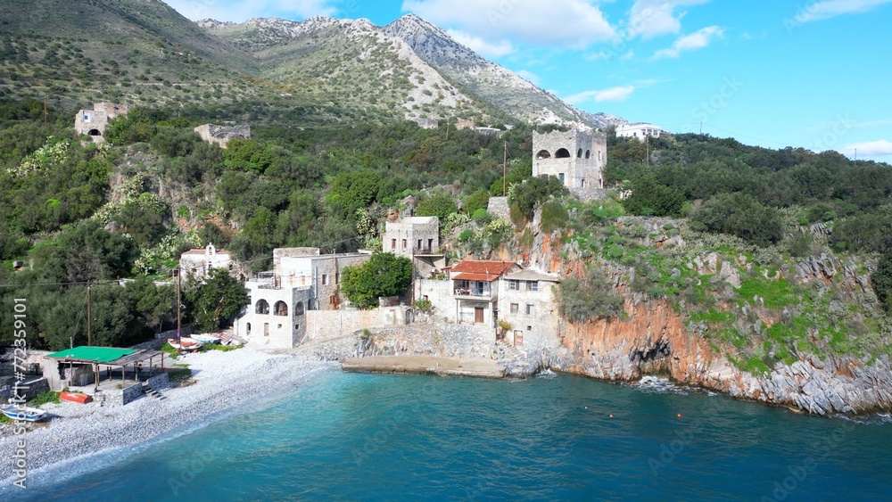Alypa Beach, Mani Peninsula, Lakonia, Peloponnese, Greece, a beautiful stone beach with a transparent and turquoise sea water and cave in a cliff - drone aerial view