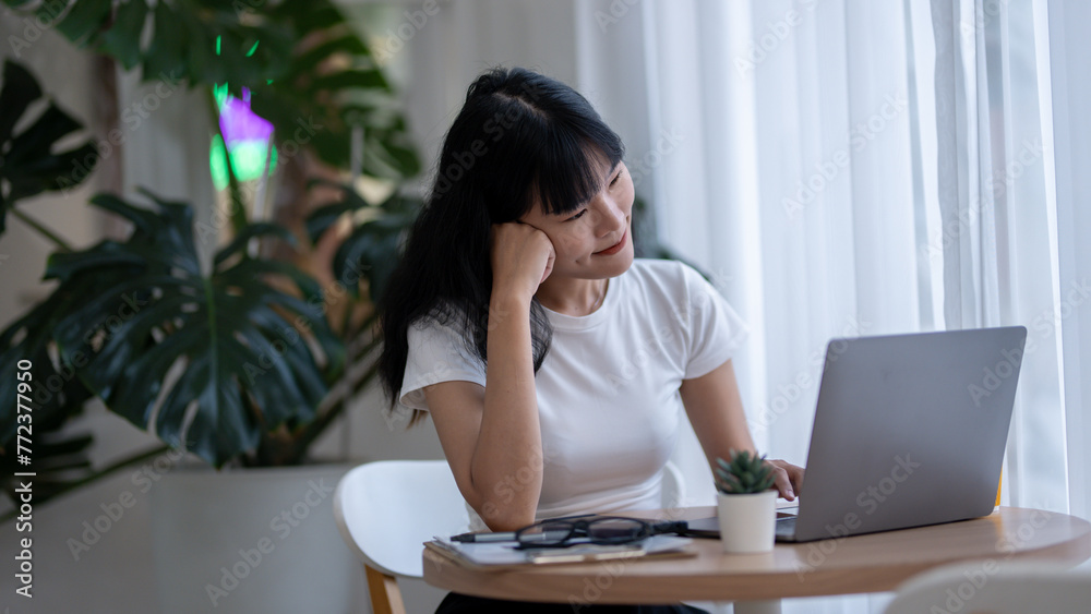 Asian woman working seriously on laptop Think and analyze plans in a bright room. Asian woman working seriously on laptop Think and analyze plans in a bright room.