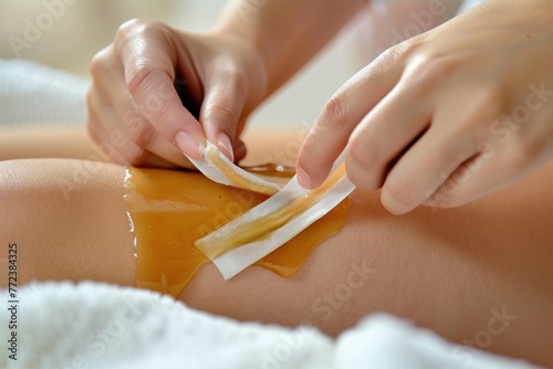 A young girl waxes her leg with a strip of wax, sugaring