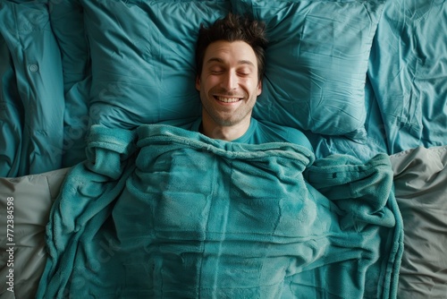 man lying in bed, resting his head on matching pillows and showing a wide