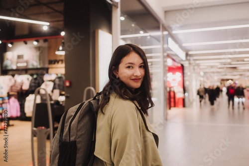 Beautiful teen girl holding shopping bags and smiling while doing shopping in mall