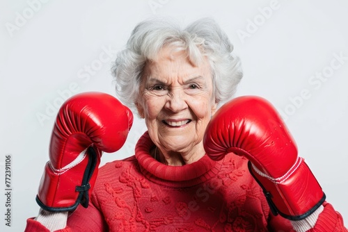 Elderly senior woman wearing red boxing gloves, confident smiling expression ready for fight