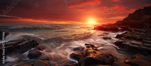 a sunset over a rocky beach with waves crashing against the rocks