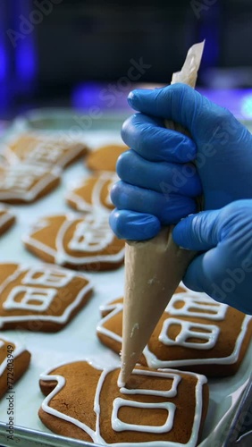 Gingerbread houses being decorated with icing. White glazing being squeezed from a pastry bag on the beautiful cookies. Close up. Vertical video photo
