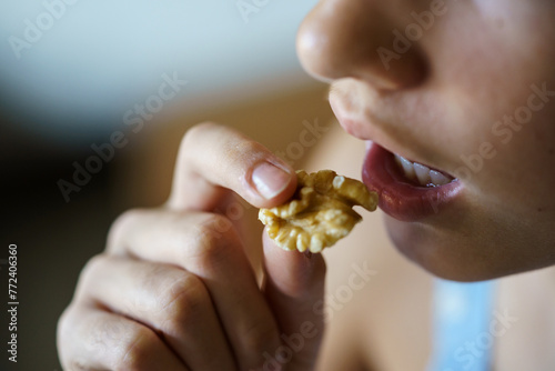 Crop anonymous teenage girl eating healthy walnut kernel
