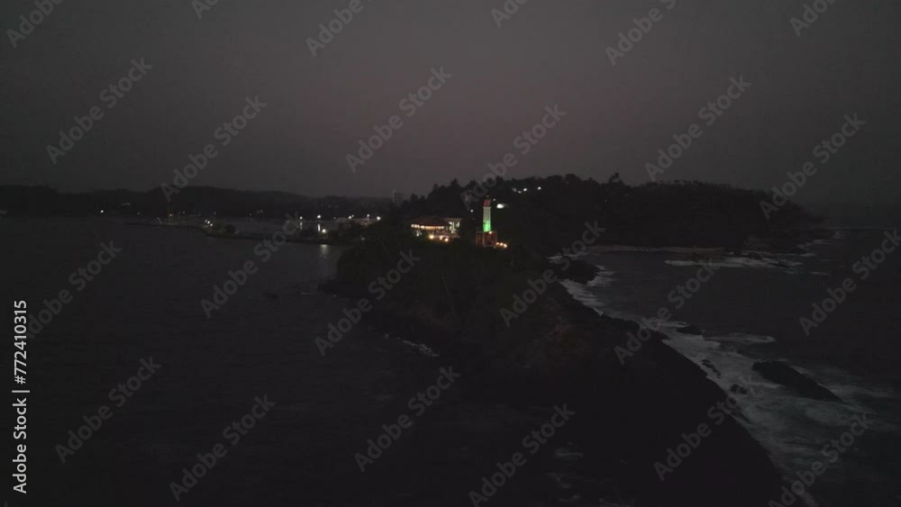 Dusk turns to night as waves crash against rocky shore, lighthouse ...