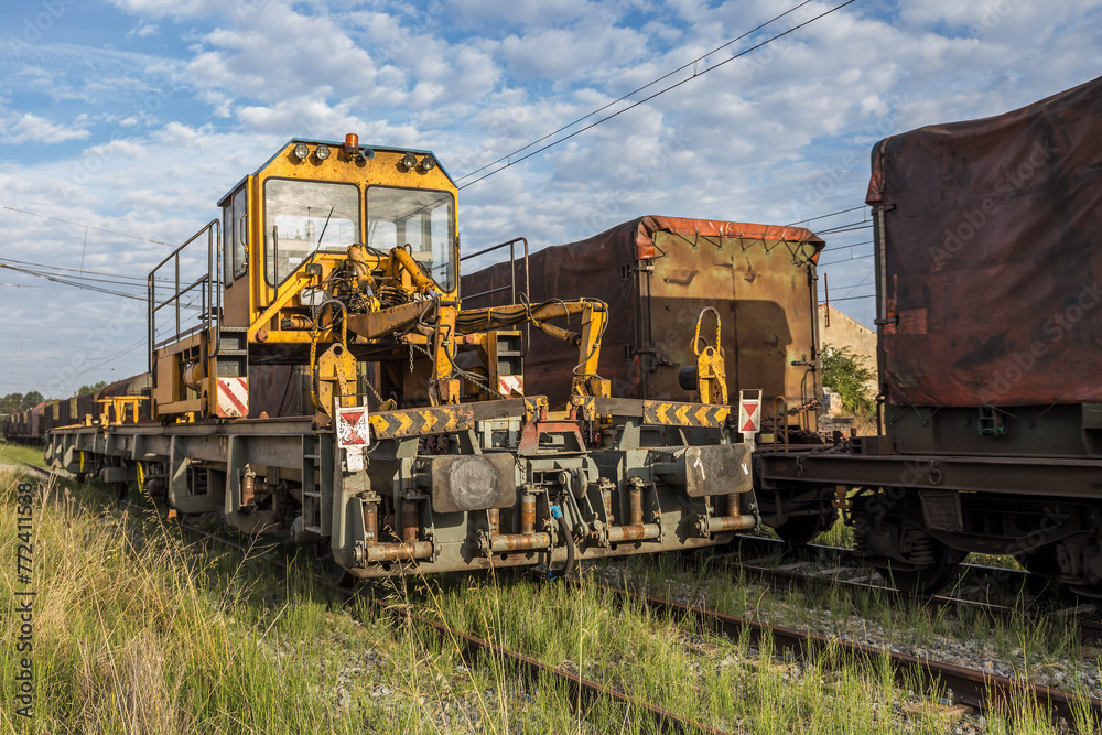 Rail train, Train intended for rail transportation made up of MMQ platforms, machine for laying rails on tracks with blue sky background and freight cars, Rail train, Train intended for rail transportation made up of MMQ platforms, machine for laying rails on tracks with blue sky background and freight cars,