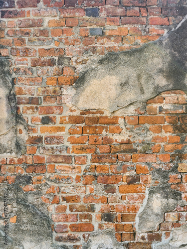 Grunge dirty old brick stone wall exterior with destroyed plaster. Background of crack old brick wall texture