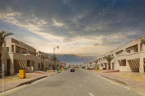 Modern Two-Story Townhouses on a Residential Street with Palm Trees and Dramatic Sky, Warm Climate Area photo