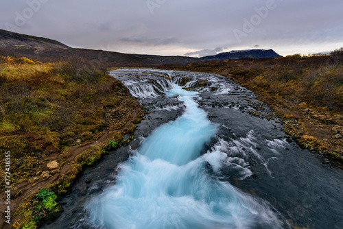 Landscape of Bruarfoss waterfall in Iceland at sunset. Bruarfoss famous natural landmark and tourist destination place. Travel and natural Concept of the Mystery of the blue Waterfall.