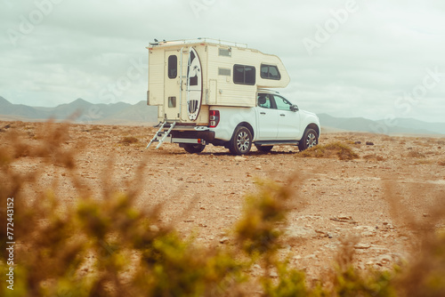 A white pick-up truck with camping facilities and surfing equipment on the coast. Fuerteventura