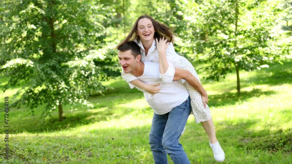 Young happy couple in love resting in nature. Woman jumped on man back, he spins her around, having fun. Concept of relaxation from the bustle of city, holidays, travel, lifestyle. Valentine's Day Young happy couple in love resting in nature. Woman jumped on man back, he spins her around, having fun. Concept of relaxation from the bustle of city, holidays, travel, lifestyle. Valentine's Day