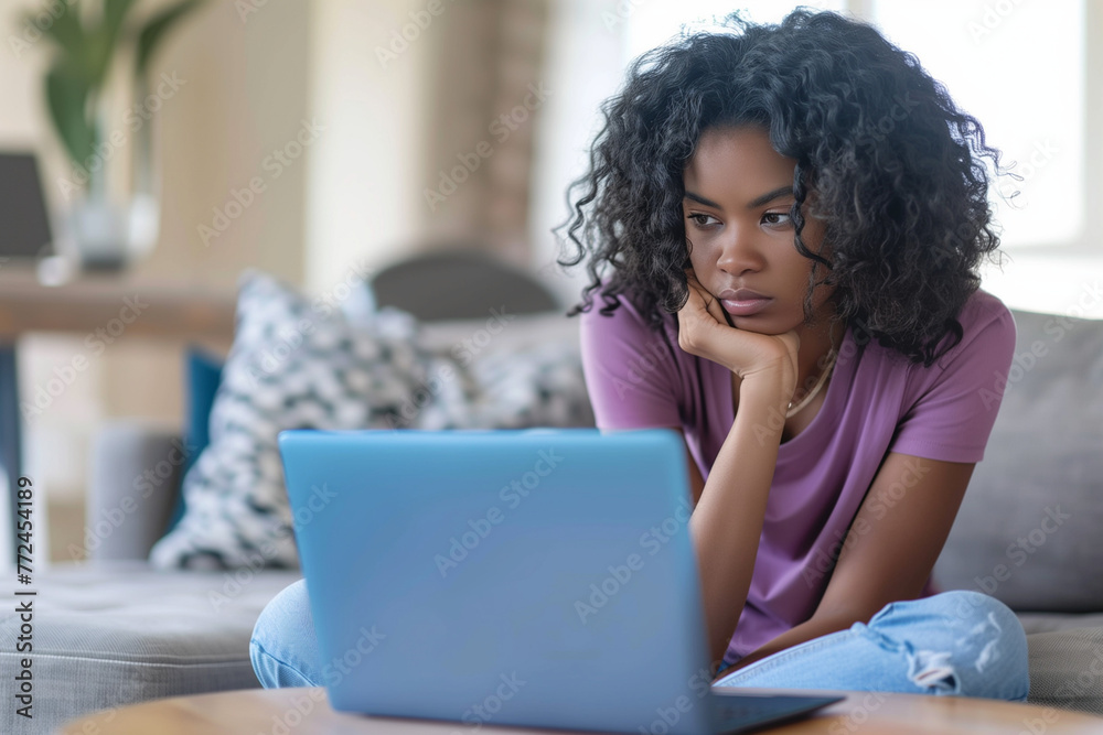 Smiling woman using a laptop on a sofa, likely working or shopping online at home Smiling woman using a laptop on a sofa, likely working or shopping online at home