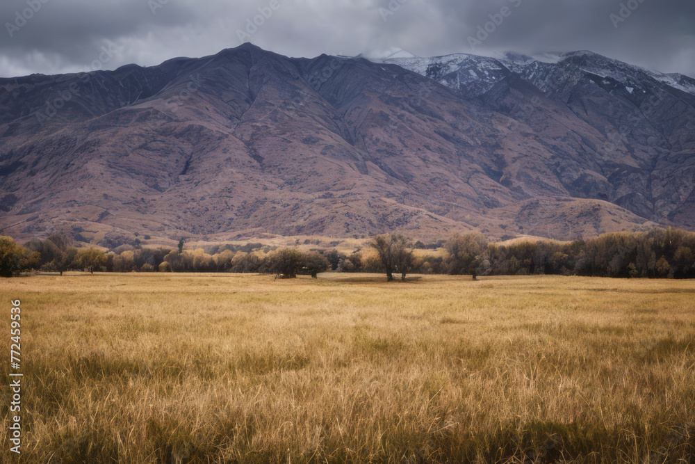 Fototapeta premium Majestic mountains ablaze with autumn colors dominate a rural landscape under a cloudy sky