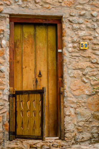 The facade of a residence with an elegant wooden door in colonial style in a beautiful stone wall architecture