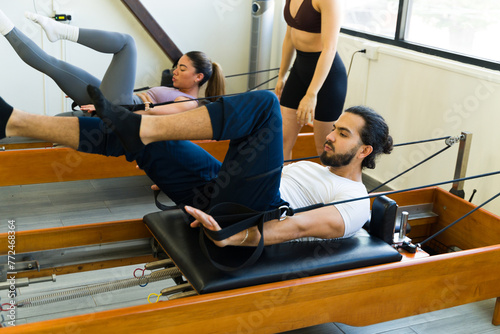 Focused man and woman practicing pilates on reformer beds in a bright studio