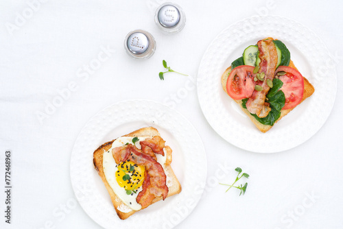  Sandwiches with fried eggs, fried ham, tomatoes, cucumbers, pepper on white background, top view.