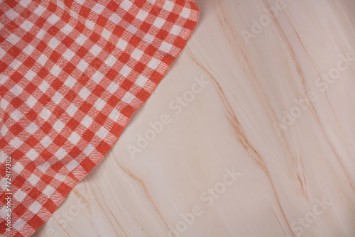 Orange checkered kitchen napkin in top corner and red on pink marble table