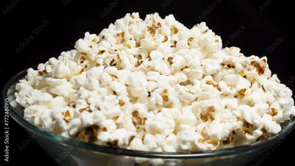 Popcorn is poured into a bowl with a heap. Rotation against a black background. Looping. Popcorn is poured into a bowl with a heap. Rotation against a black background. Looping.