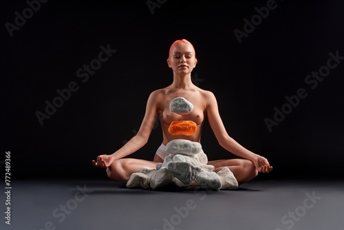 Young naked woman with closed eyes making stones levitate