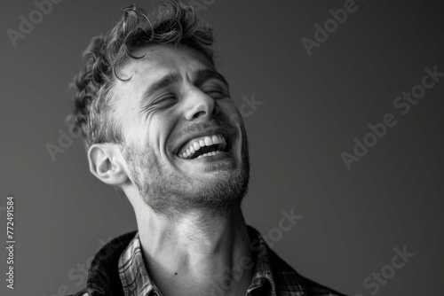 Black and white portrait of a joyful young man laughing with closed eyes, expressing genuine happiness. photo