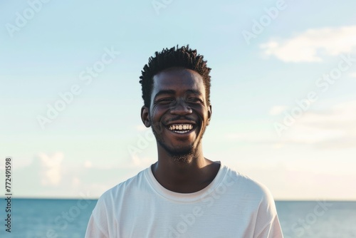Portrait of a smiling young man with the ocean in the background during sunset. photo