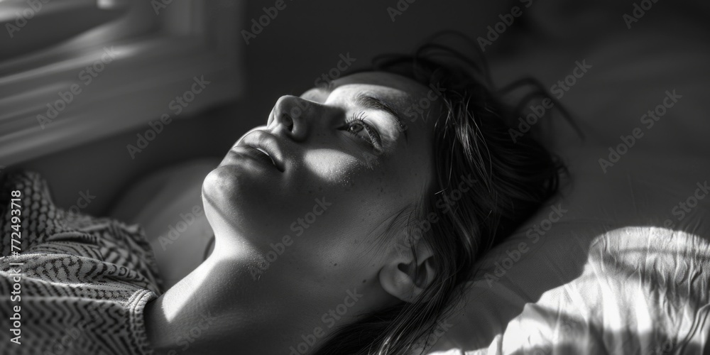 A black and white photo of a woman laying in bed. Perfect for illustrating relaxation or sleep-related concepts