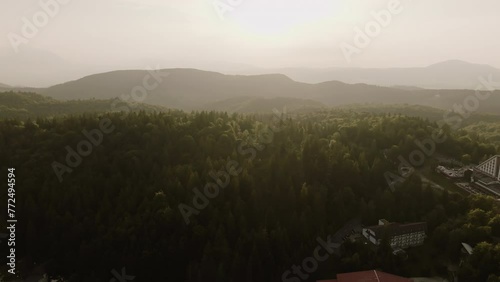 Filming with a drone a video in the midst of mountains with green forests and vacation lodges or guesthouses photo