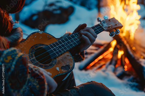 a person's hands playing a musical instrument by a campfire