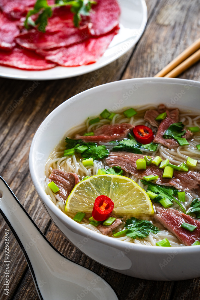 Pho soup - Vietnamese soup with beef on wooden table
