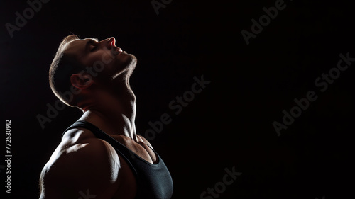 An athletic boy does stretching on a black background, copyspace