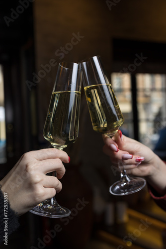 Close-up of two female hands toasting with champagne in restaurant