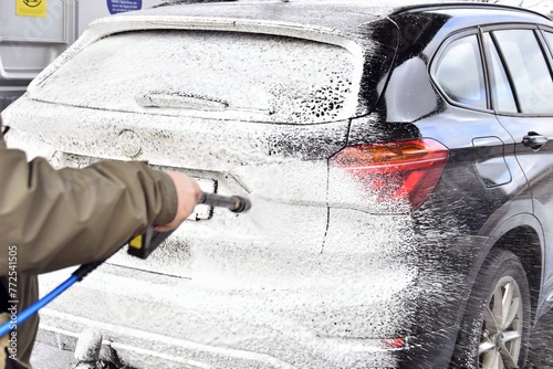 A person washing a car at a self-service car wash