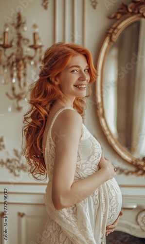 A smiling pregnant woman with red hair standing by a mirror