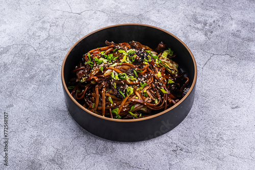 Udon with vegetables and sesame seeds on a gray background