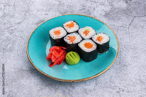 Maki sushi rolls with salmon in a plate on a gray background