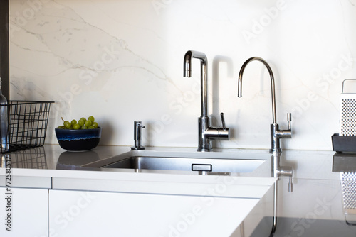 Kitchen brass utensils, chef accessories. Hanging modern kitchen with white marble wall and stone tabletop. © KatrinaEra