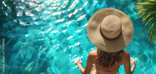woman relaxing in a pool with a large straw hat and tropical surroundings © Klay