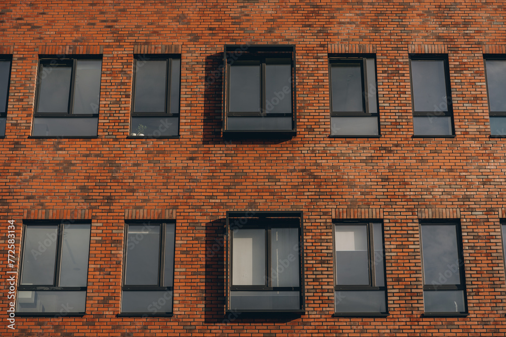 Brick red facade of modern office building, windows with rectangular decor in row