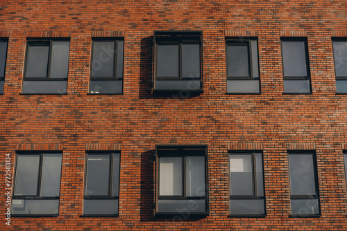 Brick red facade of modern office building, windows with rectangular decor in row