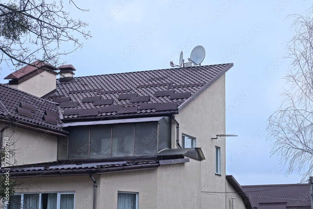 part of the roof of a private house under a tiled roof with a windows against the gray sky