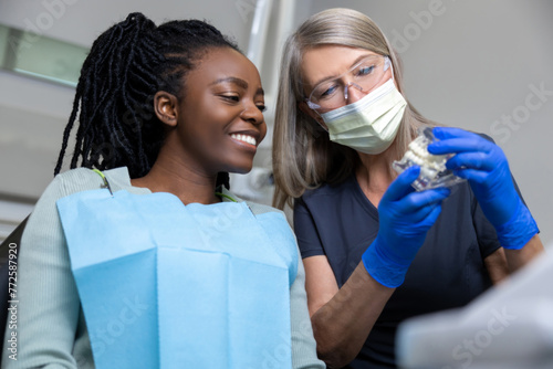 Female dentist showing dentures to her patient