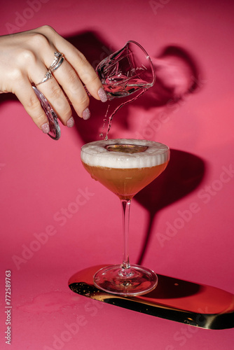 hand holding glass and pouring champagne into cocktail