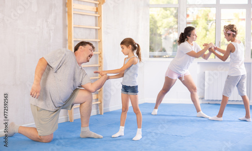 Father and daughter training self-defense techniques in studio