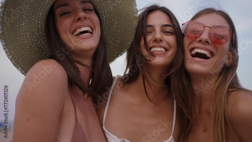 Group of caucasian girls laughing outdoors in summer having fun. Three women in bikini look happy and cheerful in vacation showing their friendship. They are in holidays enjoying together carefree