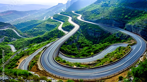 Aerial view of winding road in mountainous area with mountains in the background.