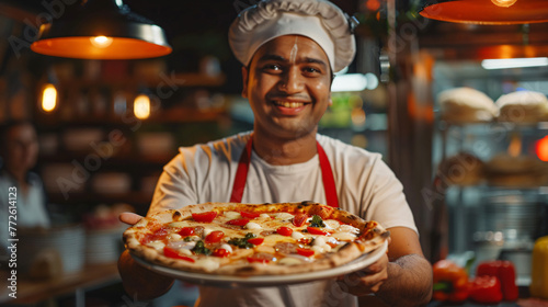 indian man with apron holding plate of pizza © fraudiana