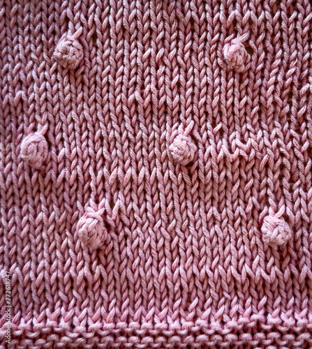 Background texture of a pink knitted baby blanket with baubles